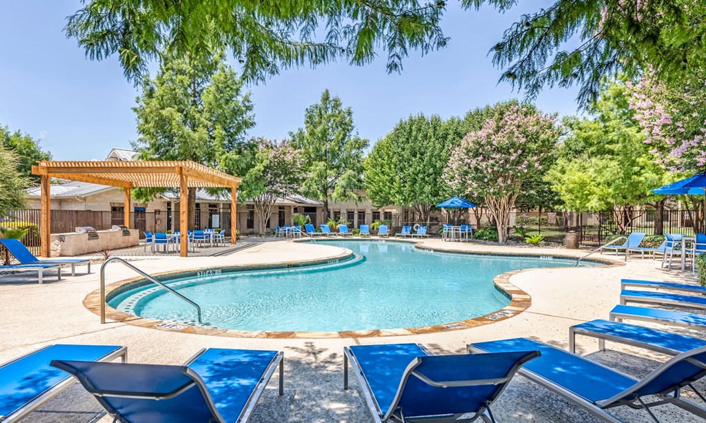Dog-Friendly Apartments in Grand Prairie, TX - Forum at Grand Prairie - Resort-Style Swimming Pool with Lounge Chairs, Umbrellas, Tables, a Picnic Area, and Beautiful Lanscaping