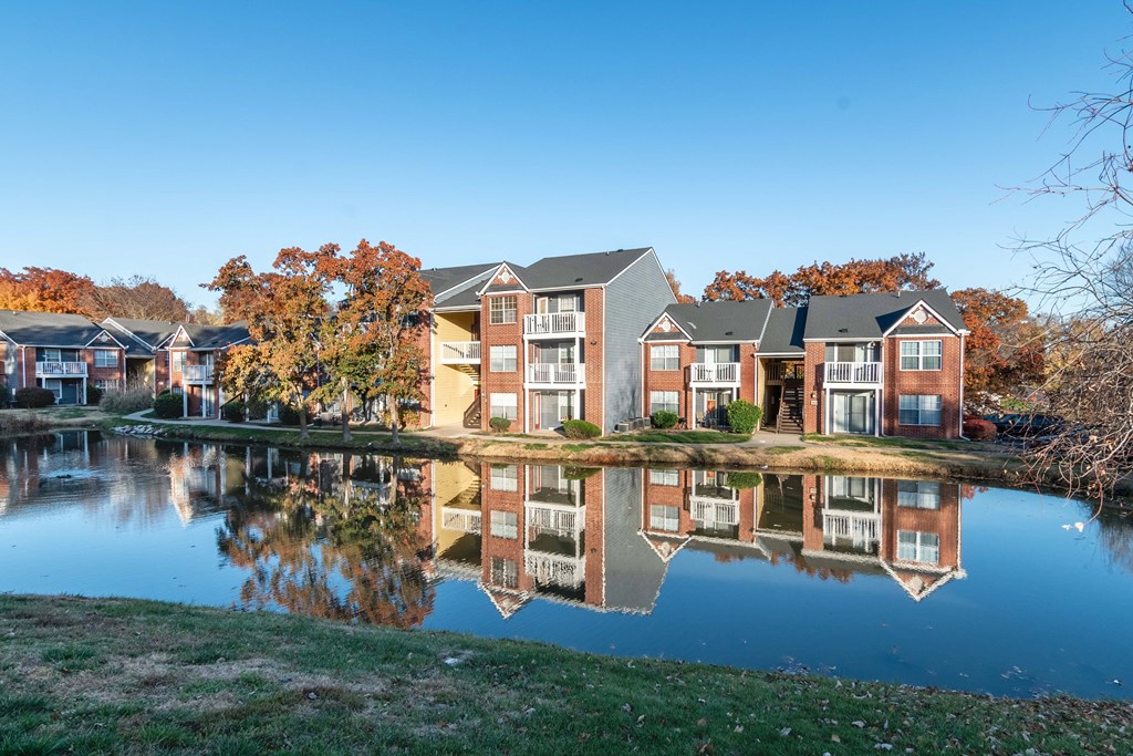 an apartment building reflected in a pond in front of it