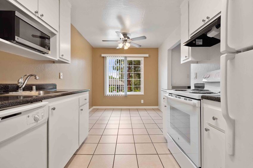 a kitchen with white appliances and a ceiling fan