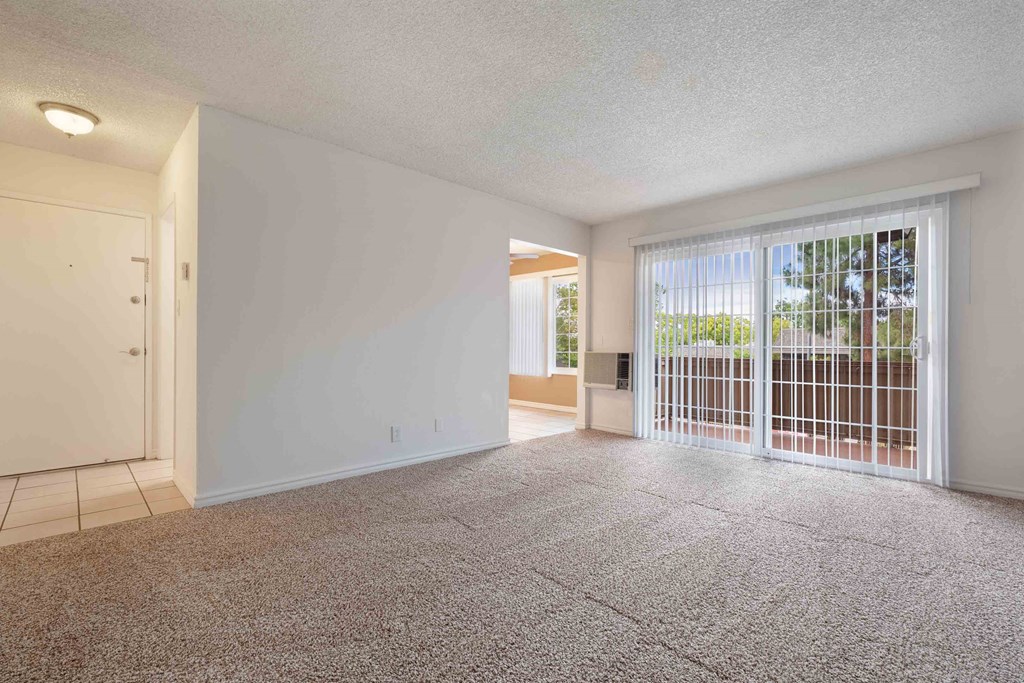 an empty living room with a sliding glass door to a patio