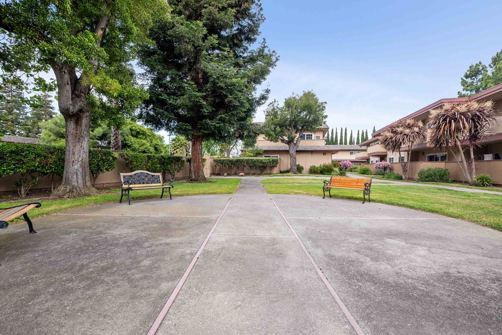a park with benches and trees in front of a building