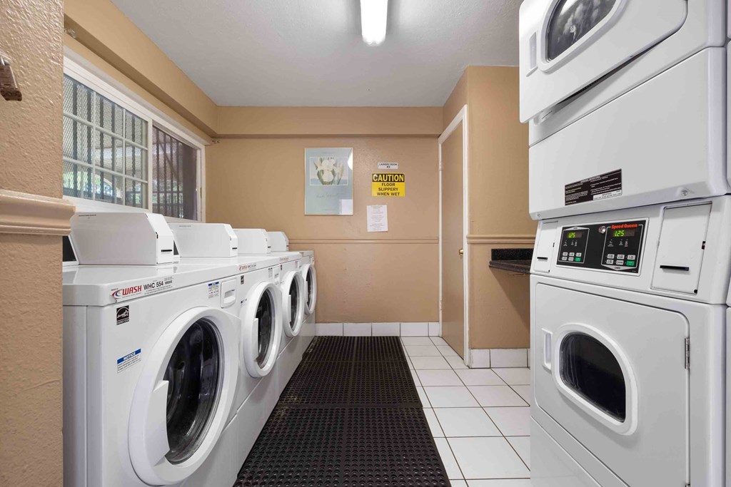 a laundry room with washers and dryers and a row of washing machines