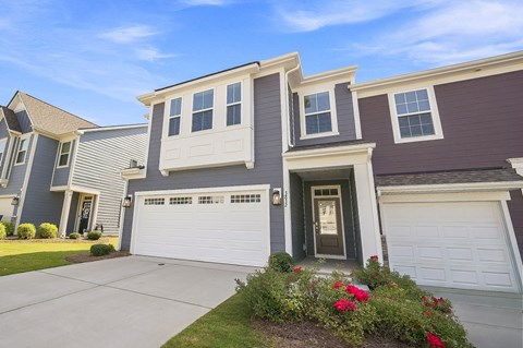 A house with a grey and brown exterior and a white garage door.