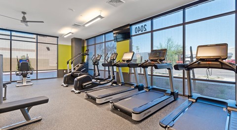 A gym with treadmills and a fan.