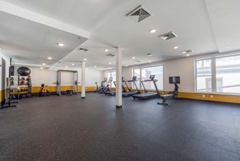 A spacious gym with various exercise equipment and a large mirror on the wall.
