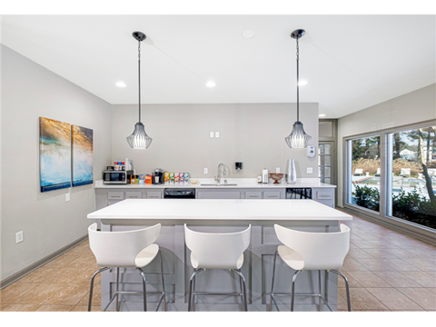the kitchen has a large island with white chairs and stainless steel appliances