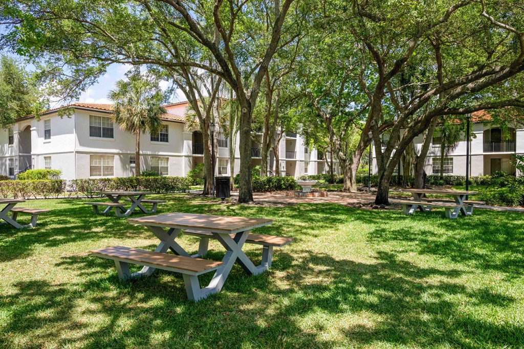 Gatehouse on the Green Apartments in Plantation, FL photo of a picnic area with benches and trees in front of an apartment building