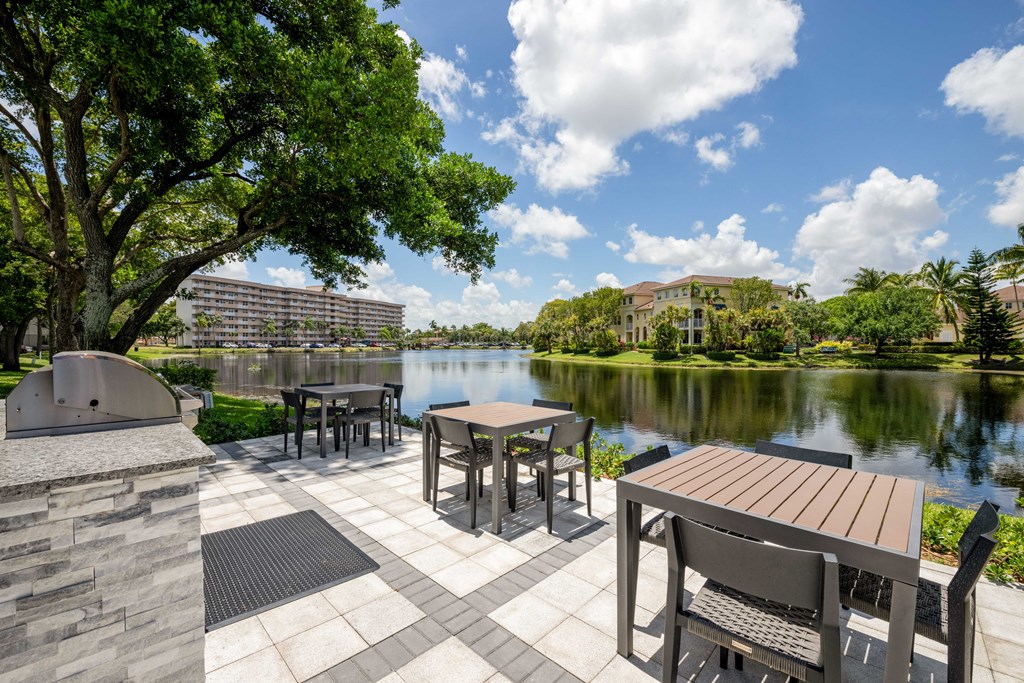Gatehouse on the Green Apartments in Plantation, FL photo of a patio with tables and chairs next to a lake