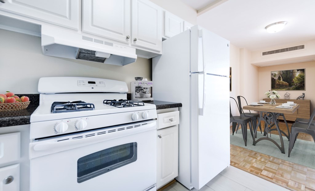 A white stove and refrigerator in a kitchen with a table and chairs in the background.
