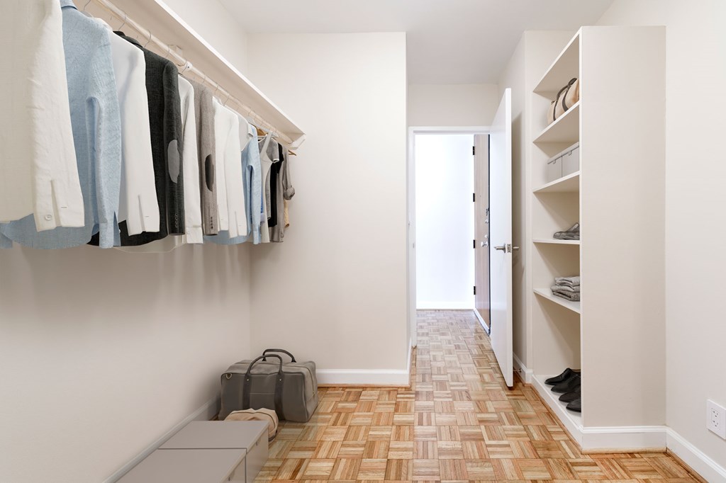 A hallway with clothes hanging on the wall and a bench.