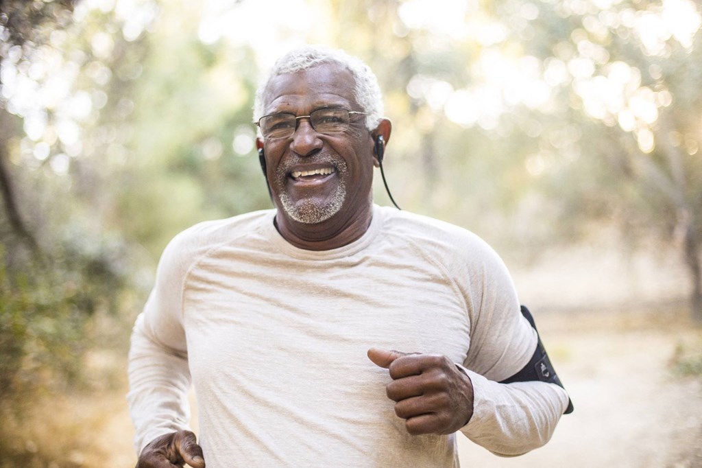 an older man smiles while running through the woods