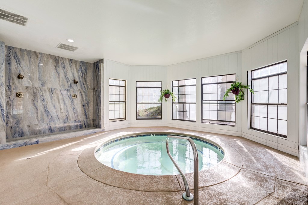 an indoor pool with marble walls in a large room with windows