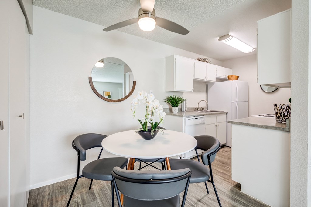 a dining area with a table and chairs and a kitchen with white appliances