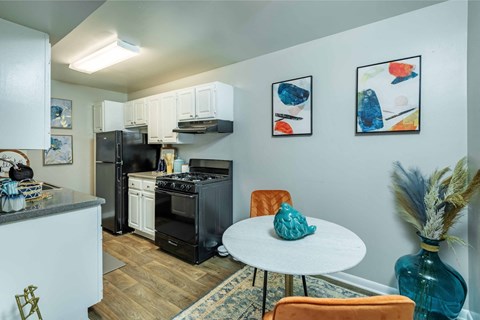 A kitchen with a black fridge and a white table.