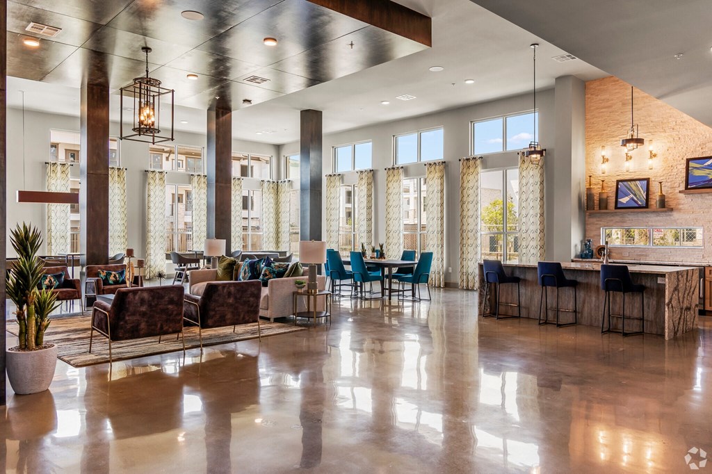 a large lobby with tables and chairs and large windows