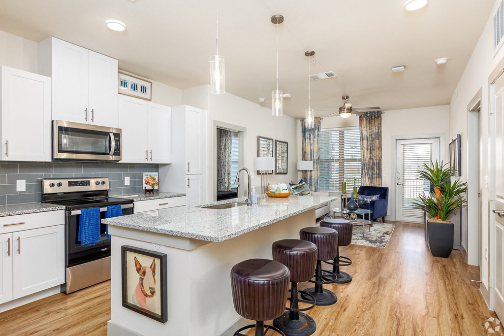 an open kitchen and living room with a bar and stools