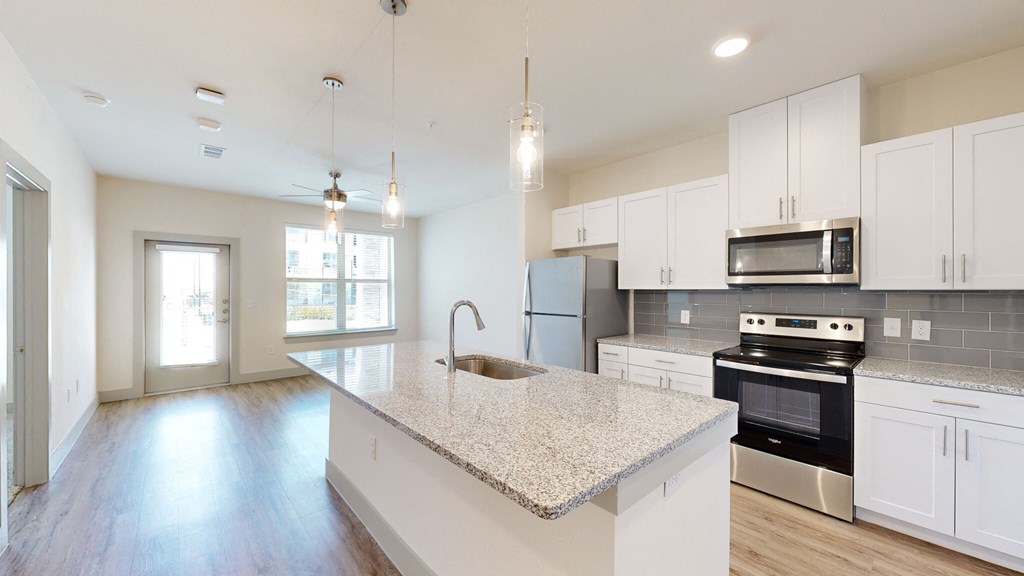 an empty kitchen with white cabinets and a marble counter top