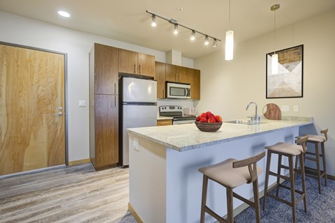 a kitchen with a large island with stools and a refrigerator