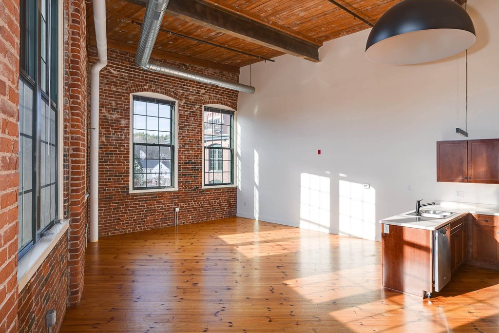 A kitchen with wooden floors and a brick wall.