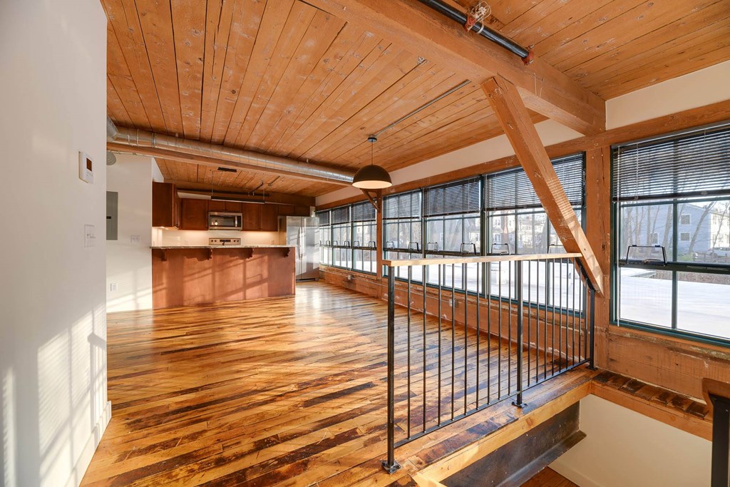 Bright, open loft apartment with wood floors, exposed beams, and large windows.