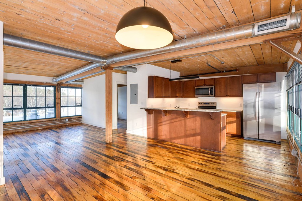 Loft apartment interior with wood floors, exposed ductwork, and kitchen.