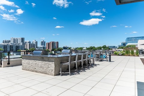 A rooftop patio with a stone barrier and several chairs.