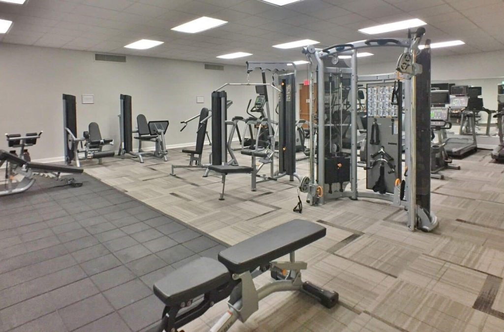 A gym with a variety of equipment including weights and benches.