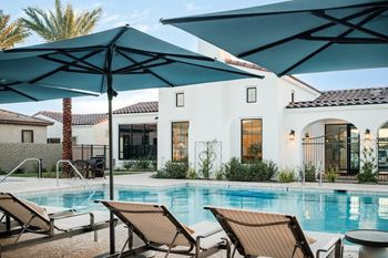 A pool with a blue umbrella and chairs.