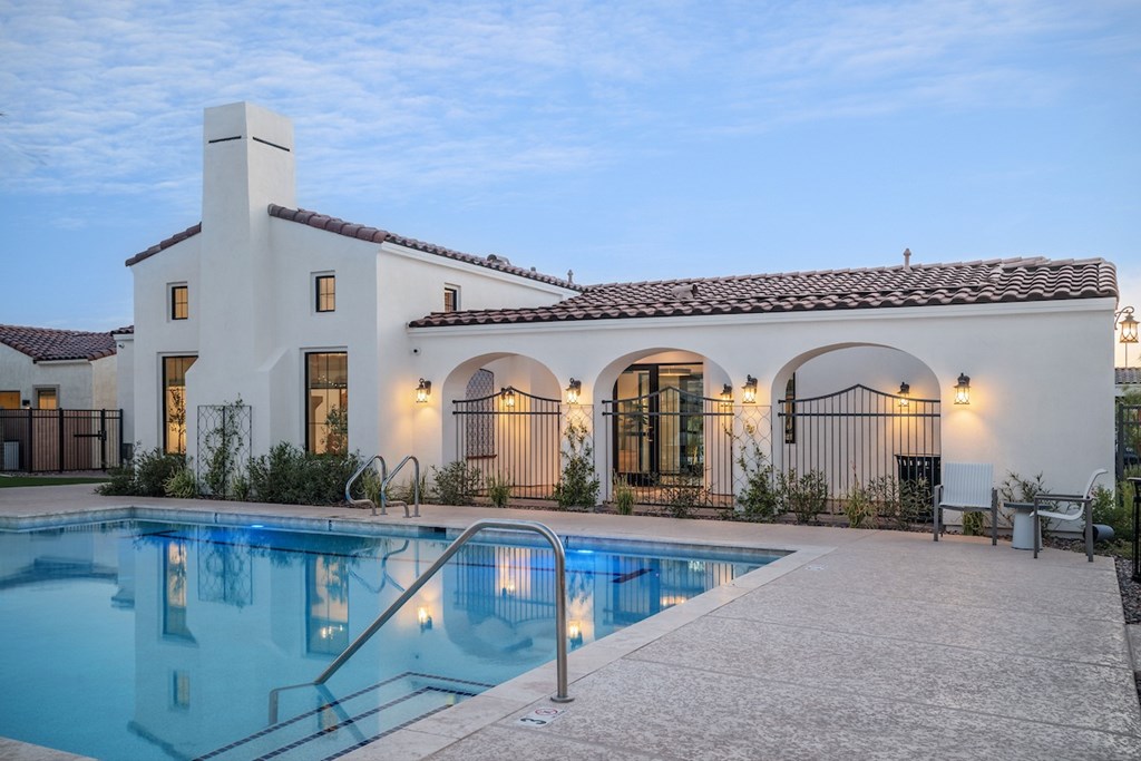 A white house with a pool in front.
