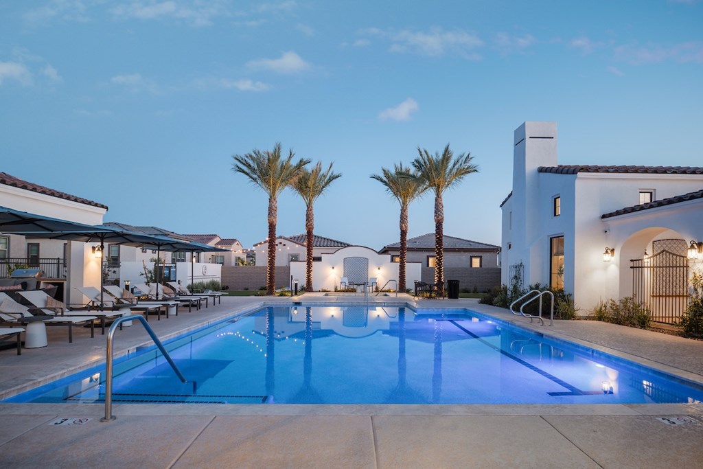 A swimming pool surrounded by palm trees and a building in the background.