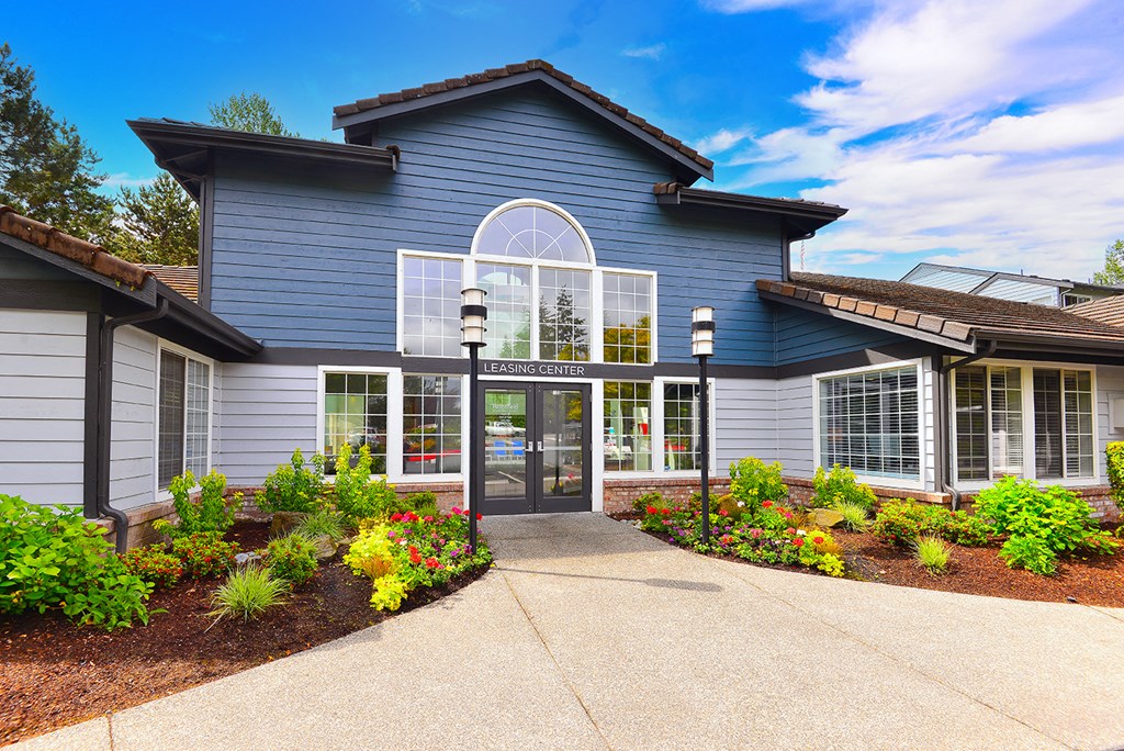 the front of a blue building with windows and a driveway