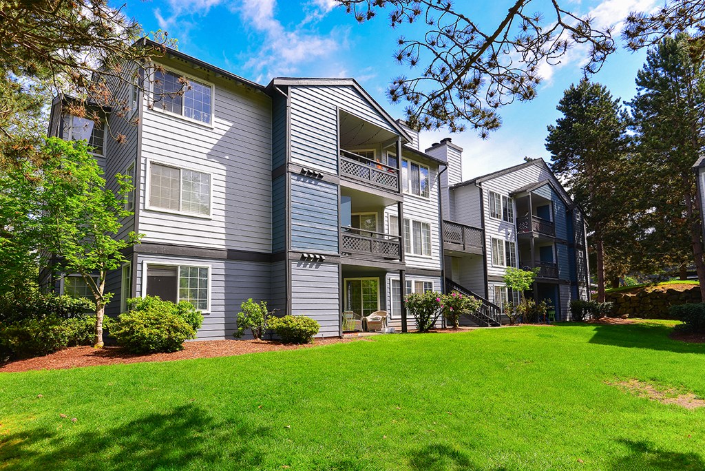a view of the exterior of an apartment building with a green lawn