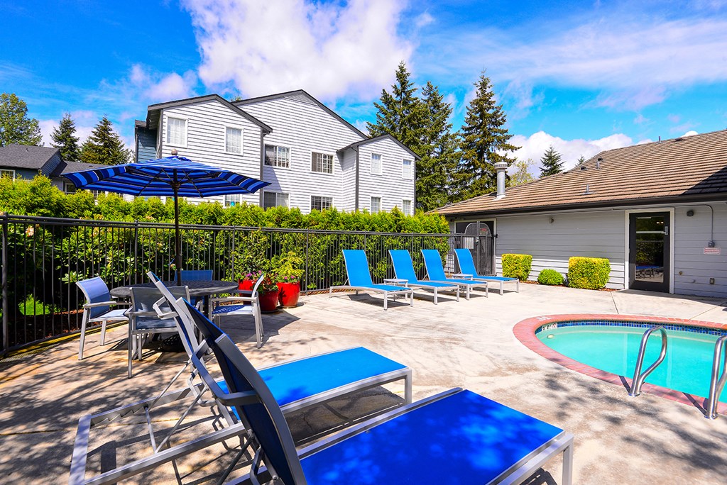 the pool and patio at the yard of a house with blue chairs and umbrella