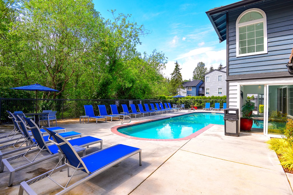 the pool is next to the house with blue chairs