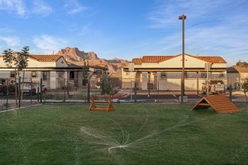 A playground with a sprinkler system in the middle of the grassy area.