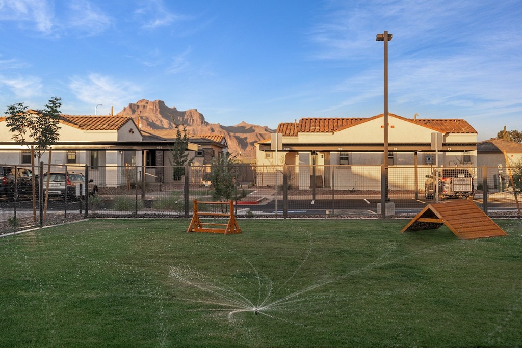 A playground with a sprinkler system in the middle of the grassy area.