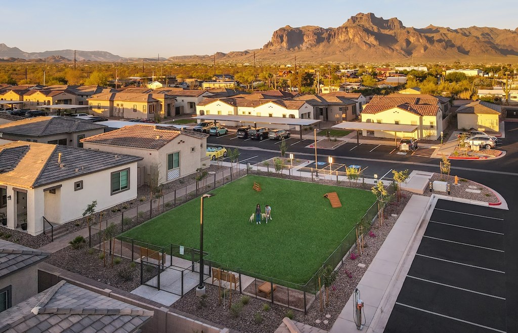 A park with a green lawn and a baseball diamond is surrounded by houses.