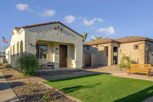 the exterior of a house with a lawn and a bench