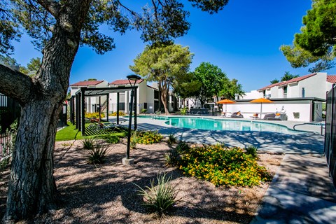 Las Vegas, NV, Apartments Near Sant Fe Station Hotel - Haven at Lone Mountain - Outdoor Resort Style Pool With Lounge Chairs, Orange Umbrellas, And Pergola Seating.