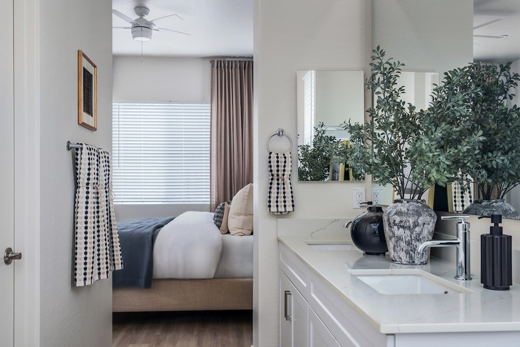 A bedroom with a bed, a mirror, and a plant.