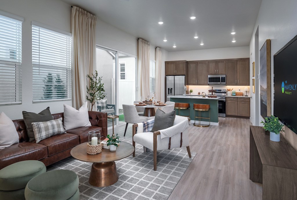 A modern living room with a brown leather couch and a television on the wall.