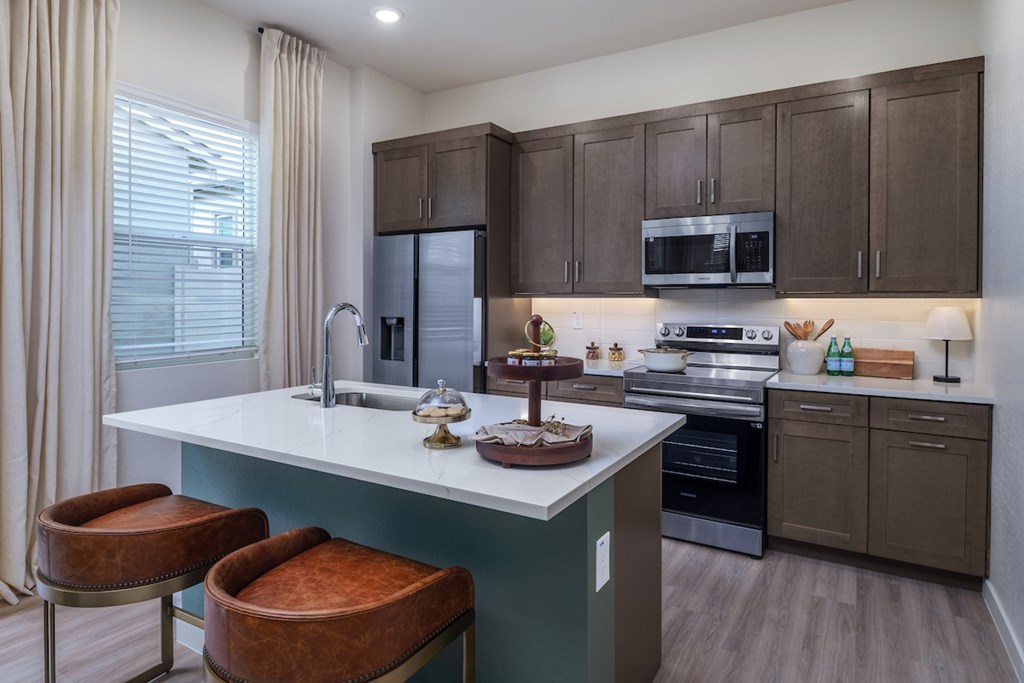 A kitchen with brown cabinets and a white island with a sink.