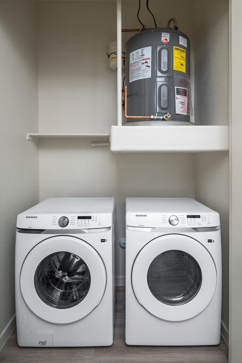 Two white front loading washing machines in a laundry room.