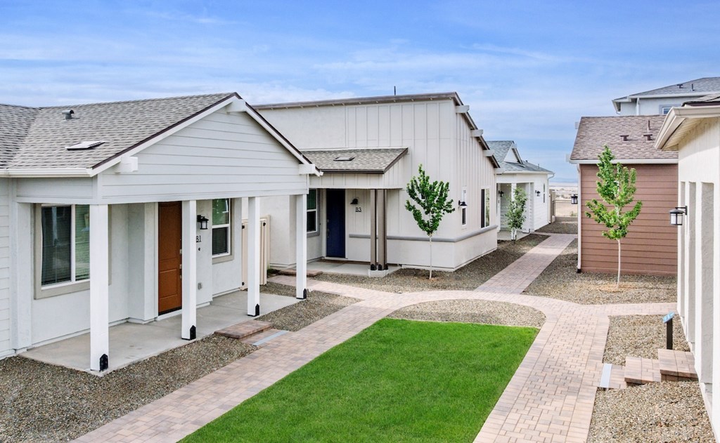 A row of houses with a green lawn in front.