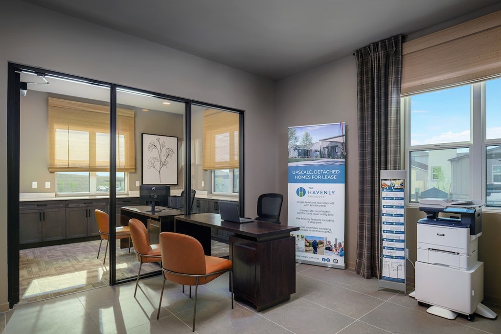 A room with a desk, chairs, and a poster on the wall.