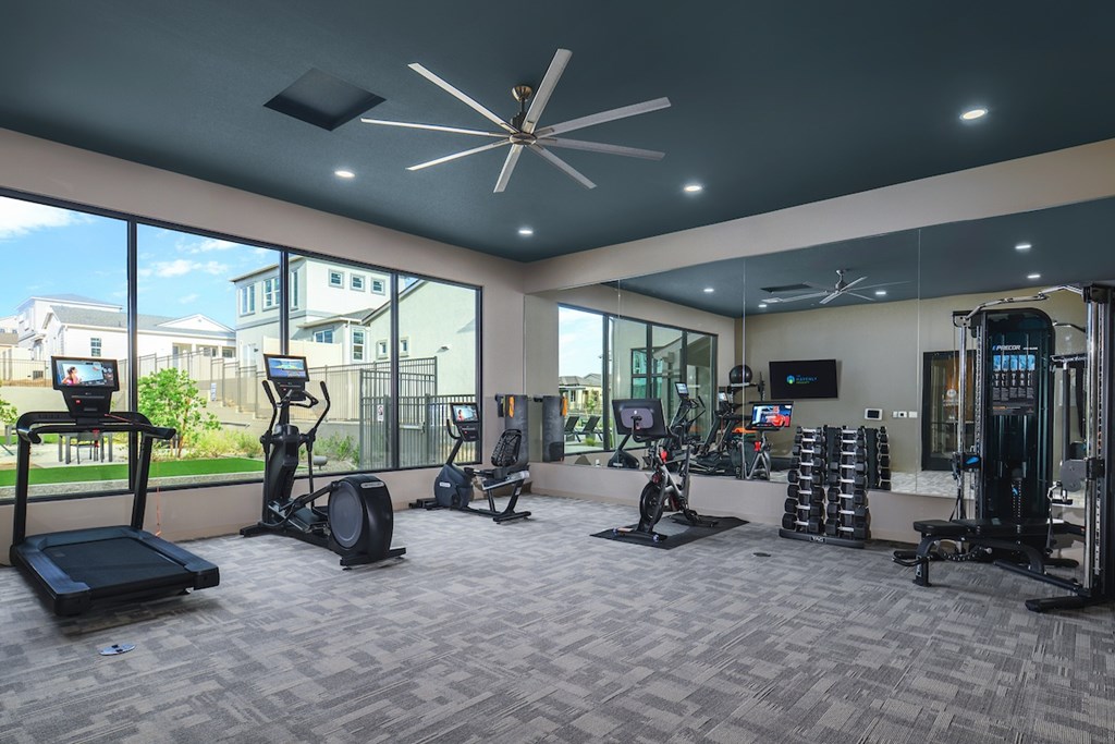 A spacious gym with a variety of equipment including treadmills, elliptical machines, and weight racks.