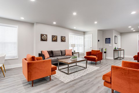 A living room with orange chairs and a grey couch.