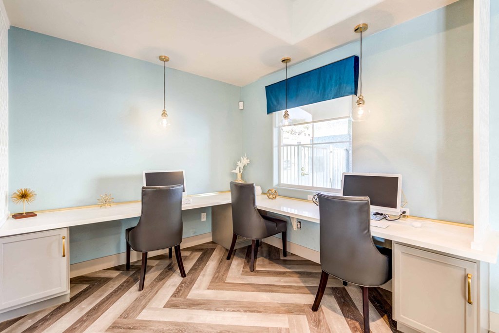 a home office with two desks and chairs and a window