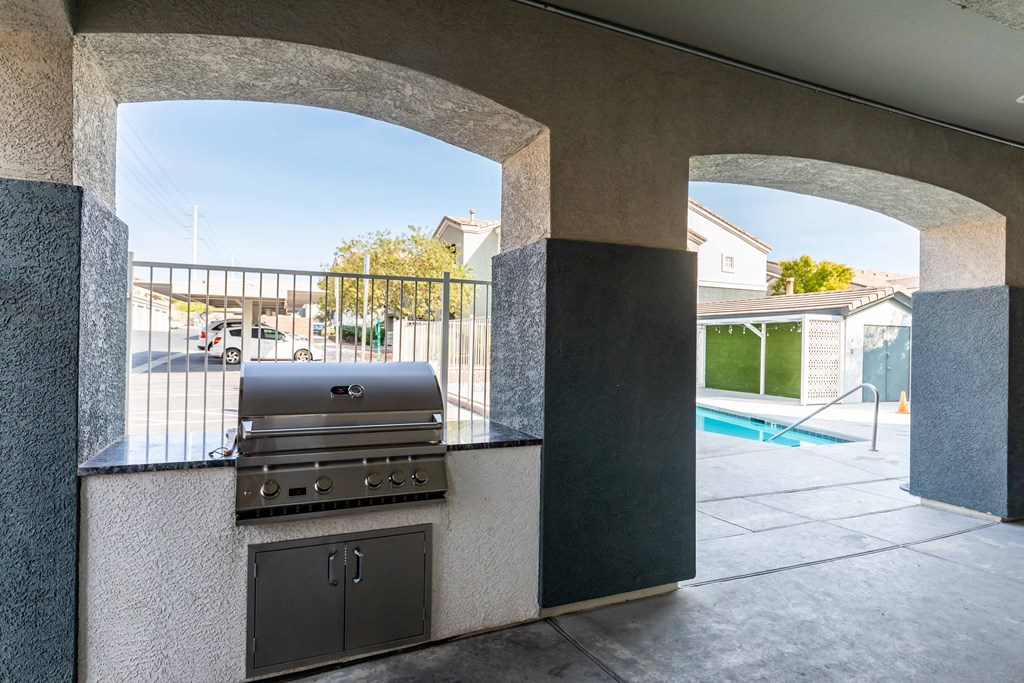 an outdoor kitchen with a grill and a swimming pool