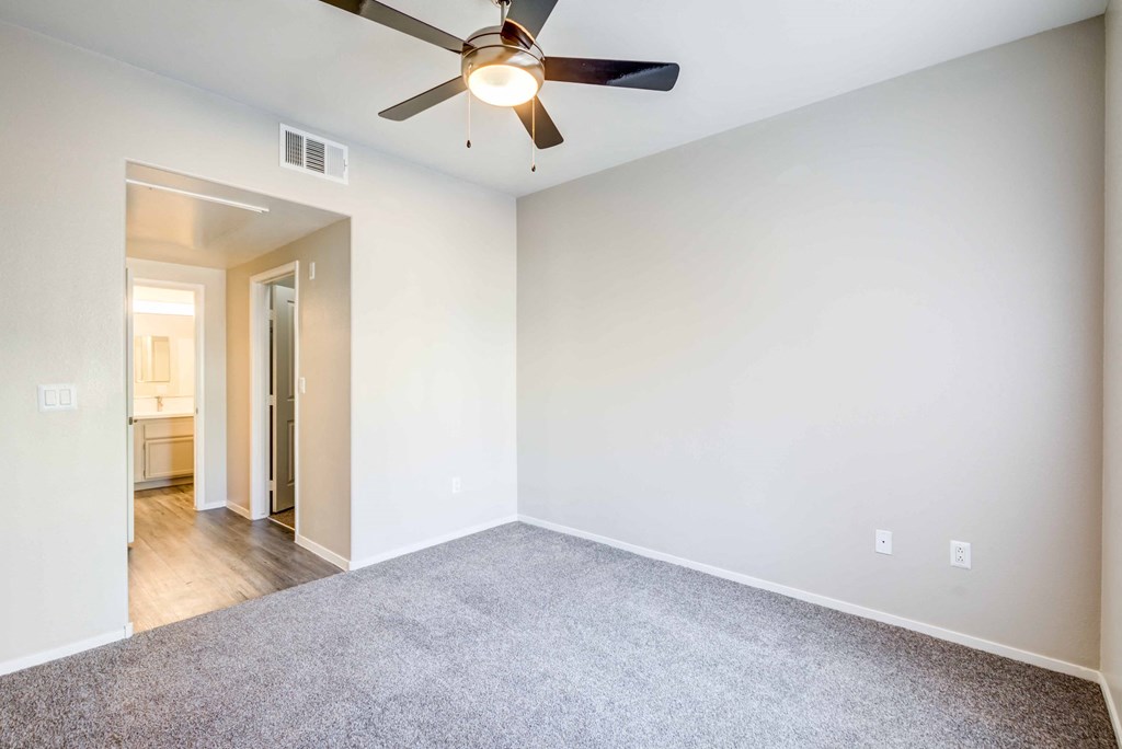 an empty living room with a ceiling fan and white walls